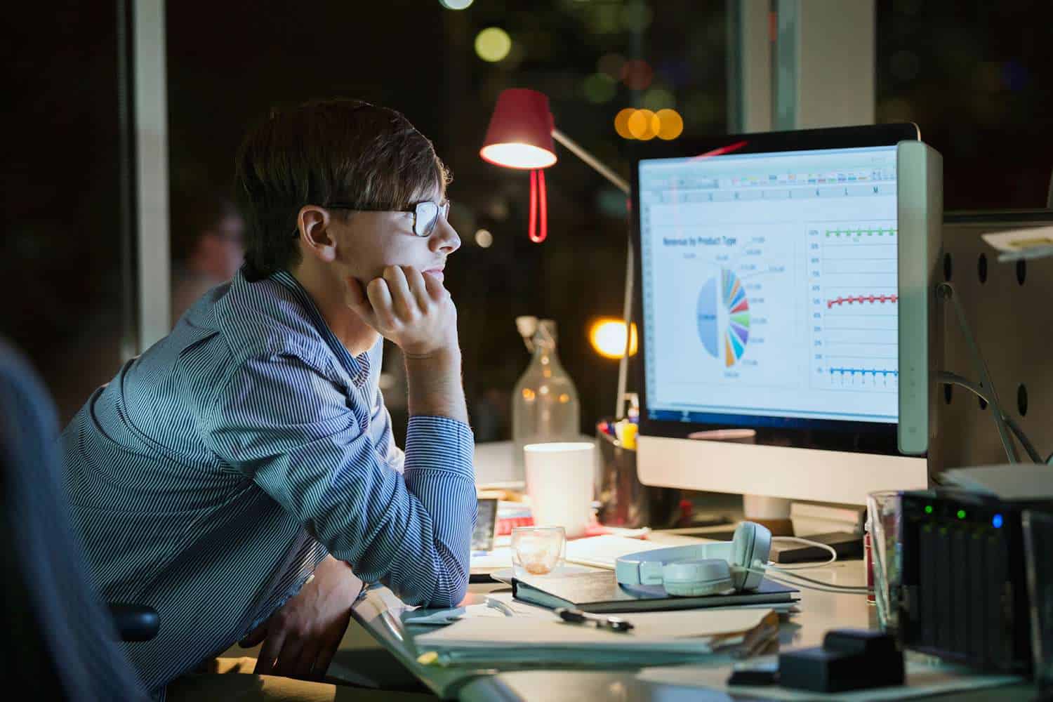 Man analyzing charts and graphs on a computer screen, tracking website and video performance late at night.