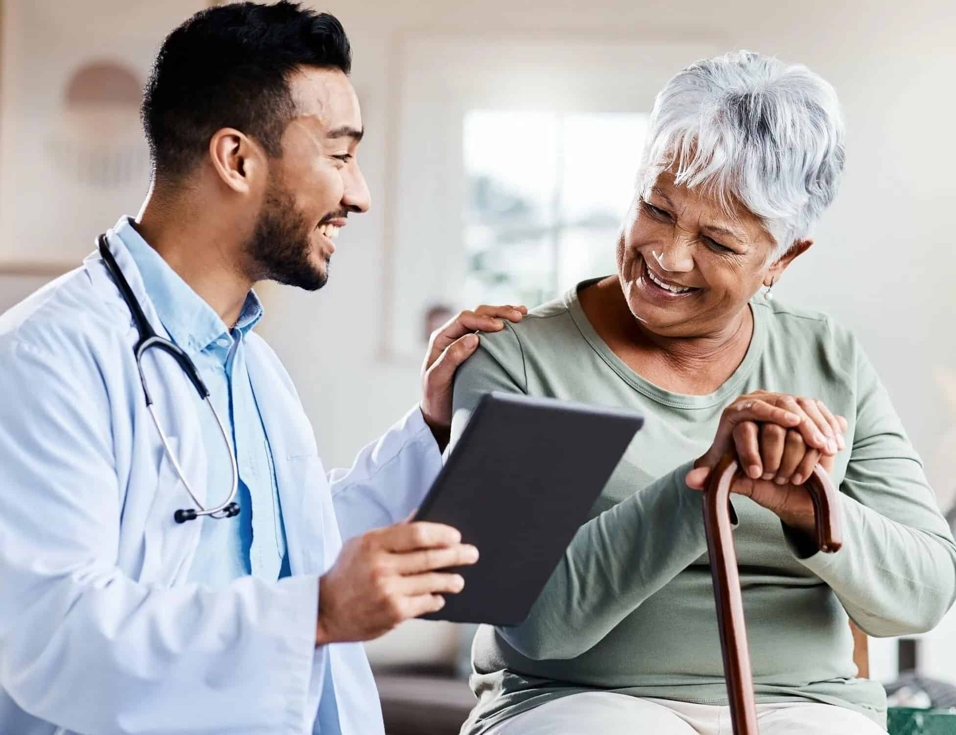 Doctor showing information on a tablet to a smiling elderly patient, illustrating clear healthcare communication.