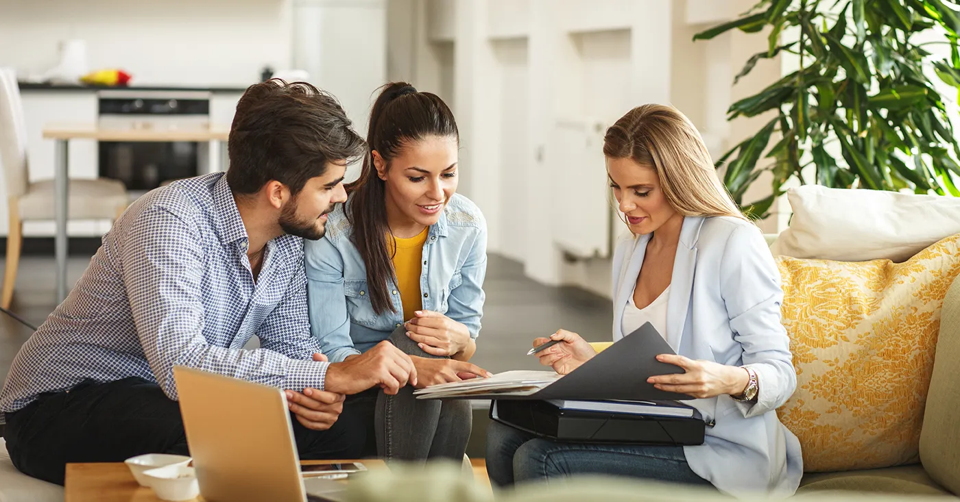 Real estate agent showing documents to a couple, symbolizing how explainer videos boost property sales and visibility.