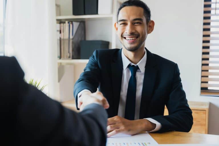 Smiling businessman in a suit shaking hands, symbolizing authenticity and trust in building strong relationships.